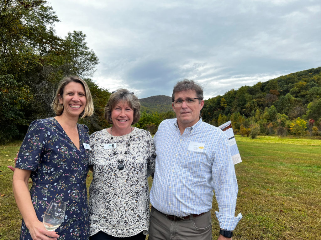 Three people standing in a field.